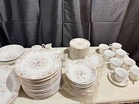 Stacked dinner plates, salad plates, bowls, cups, creamers, sugar bowls