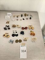 Full overhead view of all earrings and rings arranged in rows with identifying tags