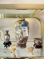 Overall lot showing yellow vase, small vase on stand, cylindrical pot on stand, two stone elephants