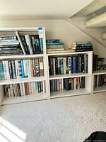 Front view of white laminated bookshelf filled with assorted books