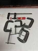 Group shot of four C-clamps and one bar clamp