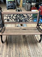 Full front view of bench showing cast iron frame, floral backrest and wood slats