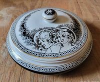Angled view of closed trinket box showing lid artwork, border and gold trim