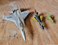 Overview of three diecast metal fighter jets laid on wooden surface