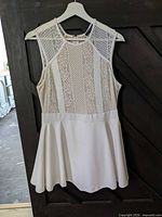 Front view of sleeveless white lace fit and flare dress on hanger