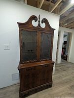 full view of china cabinet showing upper glass doors, carved crest, lower storage