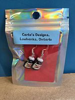 Front view of packaged earrings showing brand card and charms