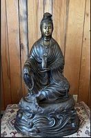 Front view of seated Buddha statue on wave-form base
