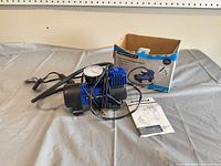 Compressor, hose, power cord, box, manual grouped on table