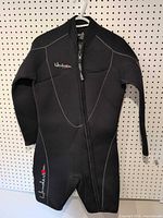 Front view of black Henderson shorty wetsuit on hanger