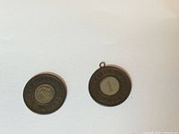 Front view of both two-tone token pendants showing numeral side and loop on one piece