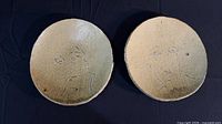 front view of both ceramic plates showing face designs
