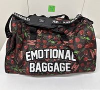 Front view showing full bag, cherry pattern and "EMOTIONAL BAGGAGE" text.