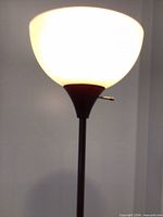 Close-up of lit frosted bowl shade atop brown holder