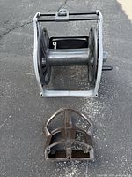 Front view of gray hose reel and brown hose holder on pavement