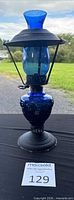 Full view of blue glass oil lamp with metal frame and base