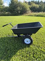 Side view of black poly dump cart trailer with hitch and pneumatic tires