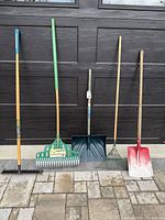 All five yard tools leaning against garage door