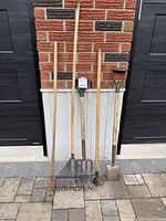 Five garden tools leaning on wall