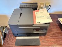 Front view of Canon PIXMA TR7020a printer with manual on top