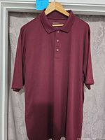 Front view of burgundy Core 365 polo hanging on hanger