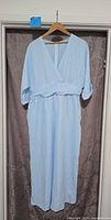 Full front view of light blue jumpsuit on hanger