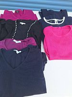 Stack of seven knit tops showing colors, necklines and cardigans