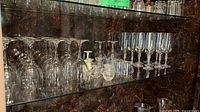 Shelf with clear wine glasses, ivory candlestick, small clear bud vases