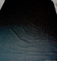 Full view of dark speckled fabric spread over queen mattress