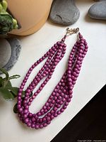 Full view of necklace laid flat showing five magenta wood bead strands and clasp