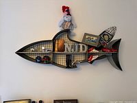 Front view of shark-shaped metal wall shelf with mesh backing and cubbies