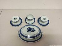 Full lot front view showing tureen with lid on underplate, two candlesticks on drip plates, cup and saucer