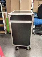 Front view of closed flight case on casters showing black panels and silver edging