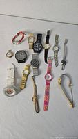 Full group shot of 14 watches laid out on white background