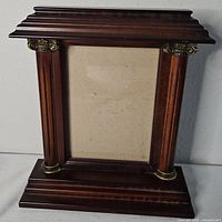 Front view showing wood finish, columns, brass accents