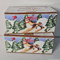Two factory-sealed boxes labeled Set of 2 "Penguin Frolic" Ceramic Cocoa Mugs by Debbie Mumm