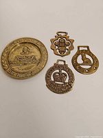 Group view of brass Shakespeare plate and three horse brasses