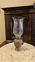 Full view of oil lamp with etched glass chimney on brass base
