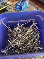 Blue tote filled with assorted metal pegboard hooks