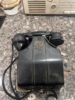 Top view of black Bakelite magneto desk telephone showing handset, TMC logo and general wear