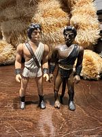 Front view of both action figures standing upright on wooden surface