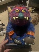 Front view of My Pet Monster plush seated in original box showing colors, cuffs, chain