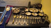 Entire lot on countertop showing flatware rows, dishes, infusers, cups