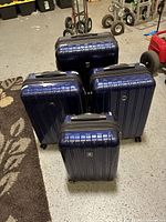 Four navy hard-shell spinner suitcases standing upright