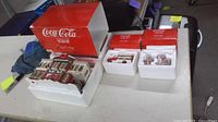 Overall lot with three Coca-Cola red boxes opened showing styrofoam inserts and contents