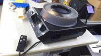 Projector angled view showing slide tray and wired remote