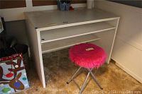 White kids desk with two shelves underneath, shown with pink furry stool on carpet