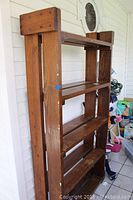 Side view of dark stained wooden bookcase showing thick planks and rustic design, visible wear and scratches.