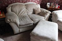 Beige microfiber suede-like loveseat and matching ottoman viewed from front right angle, showing cushions and seating area.