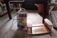 Photo of white metal towel dryer with five horizontal rungs, bag of Poly Fil polyester fiber, and wooden lap tray table under table in carpeted room.